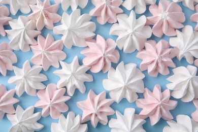 Tasty meringue cookies on light blue background, flat lay