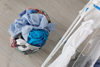 Photo of Plastic laundry basket overfilled with clothes in bathroom, flat lay