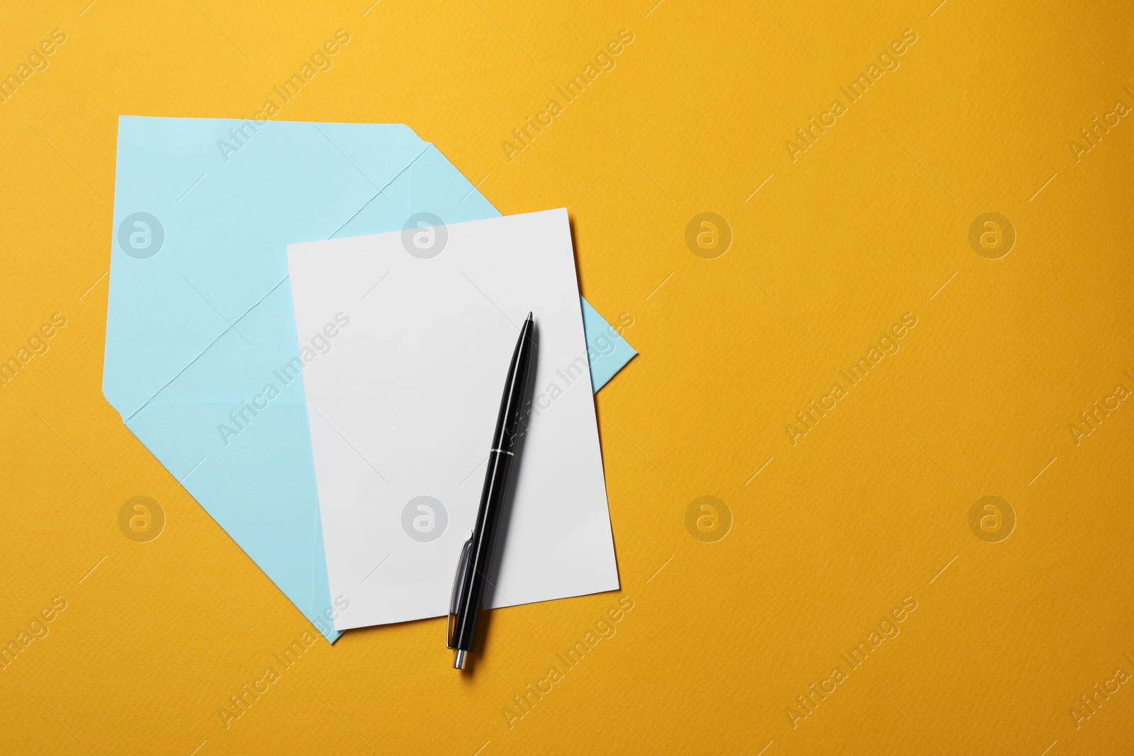 Photo of Blank sheet of paper, letter envelope and pen on orange background, top view. Space for text