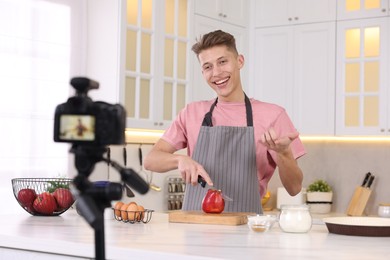 Photo of Smiling food blogger cooking while recording video in kitchen