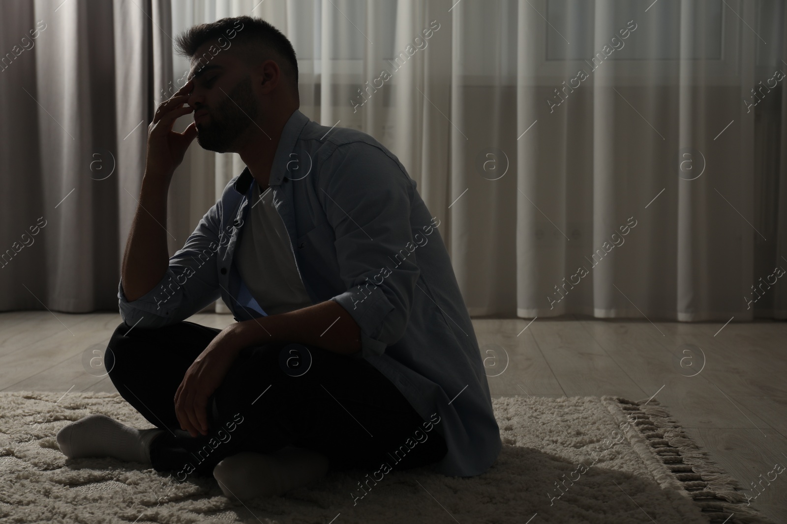 Photo of Sad man sitting on floor near window. Space for text