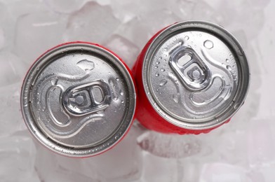 Energy drinks in wet cans on ice cubes, flat lay