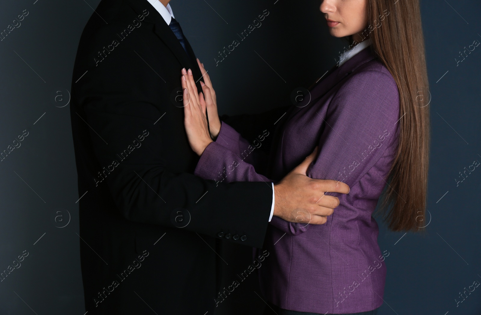 Photo of Boss molesting his female secretary on dark background, closeup. Sexual harassment at work