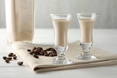 Coffee cream liqueur in glasses and beans on white wooden table