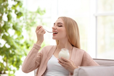 Photo of Young woman with yogurt indoors