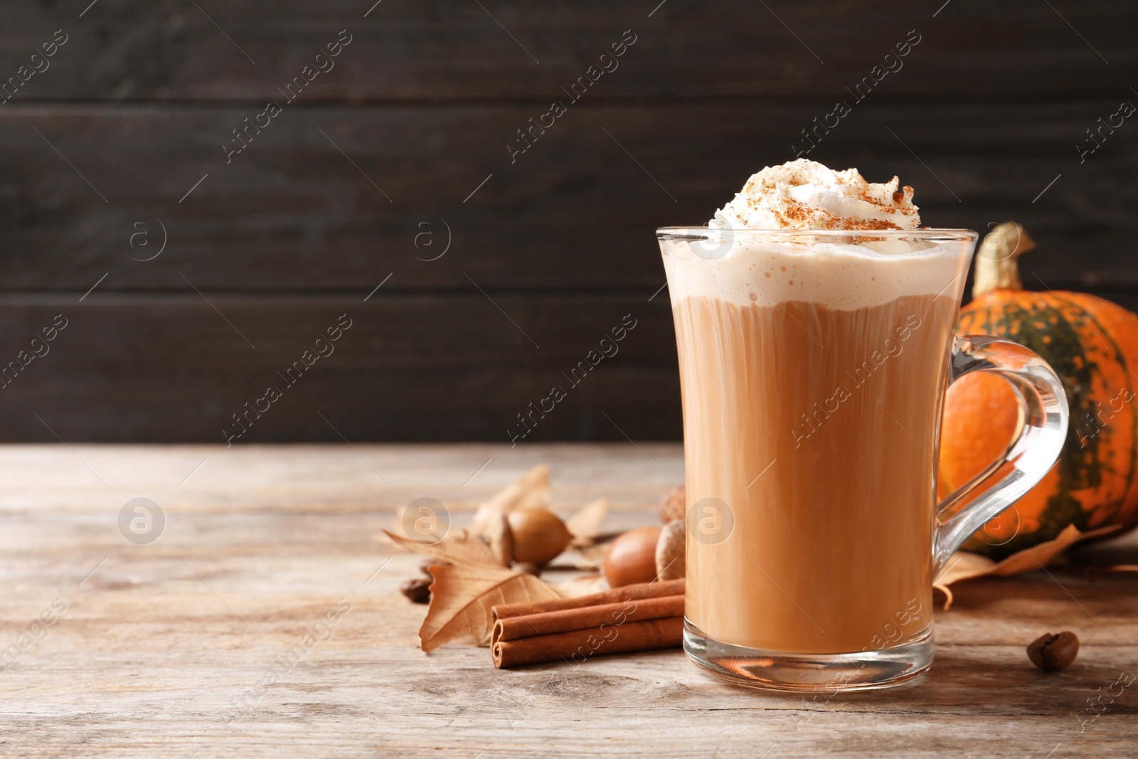 Photo of Glass cup with tasty pumpkin spice latte on wooden table. Space for text