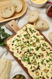 Photo of Fresh butter board with cut olives, sun-dried tomatoes and bread on table, flat lay