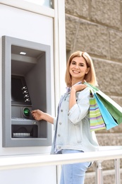 Photo of Beautiful woman using cash machine for money withdrawal outdoors
