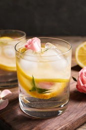 Photo of Delicious refreshing drink with lemon and roses on wooden table