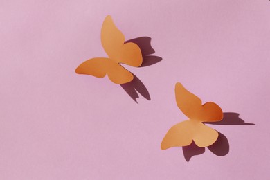 Bright orange paper butterflies on pink background