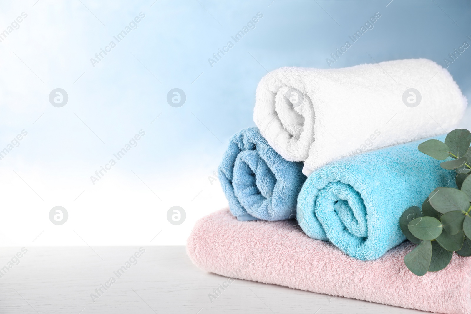 Photo of Rolled bath towels on white wooden table. Space for text