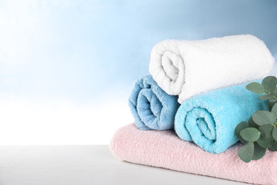 Rolled bath towels on white wooden table. Space for text