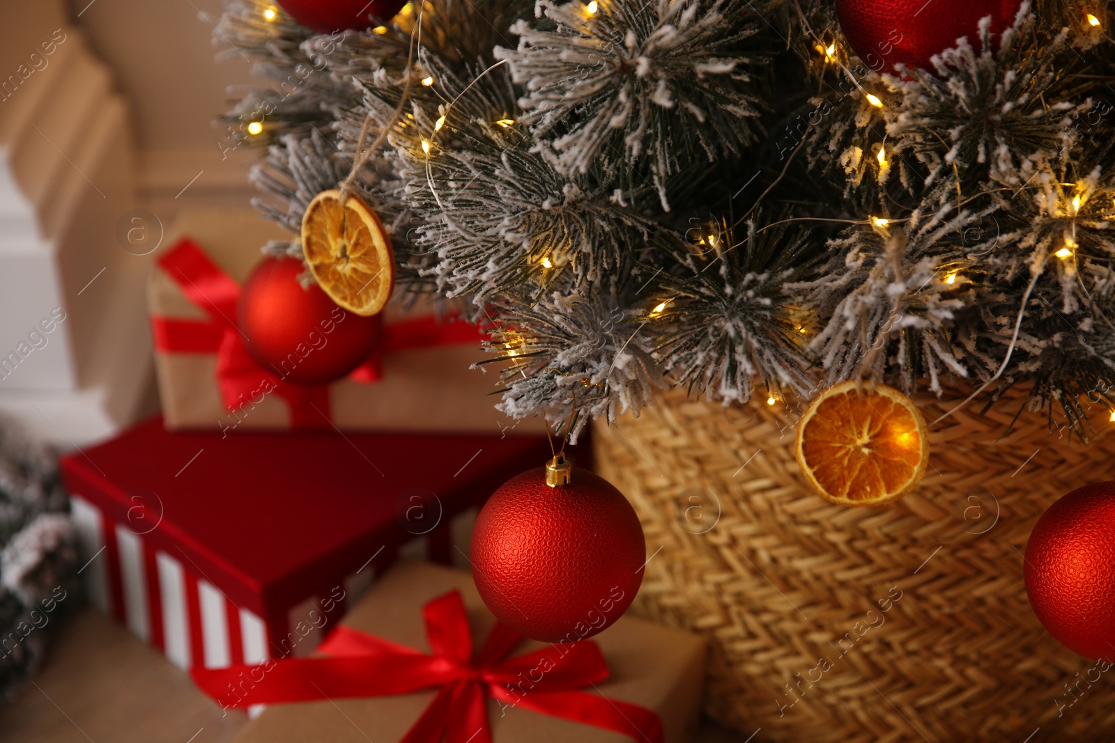 Photo of Beautiful Christmas tree decorated with red balls, dried orange slices and fairy lights in room, closeup