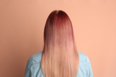 Photo of Woman with bright dyed hair on pale pink background, back view