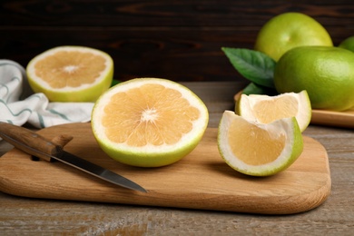 Photo of Cut fresh sweetie fruit and knife on wooden board