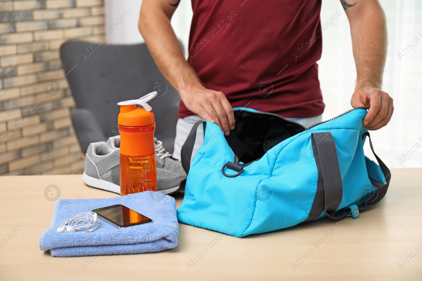 Photo of Young man packing sports bag on table