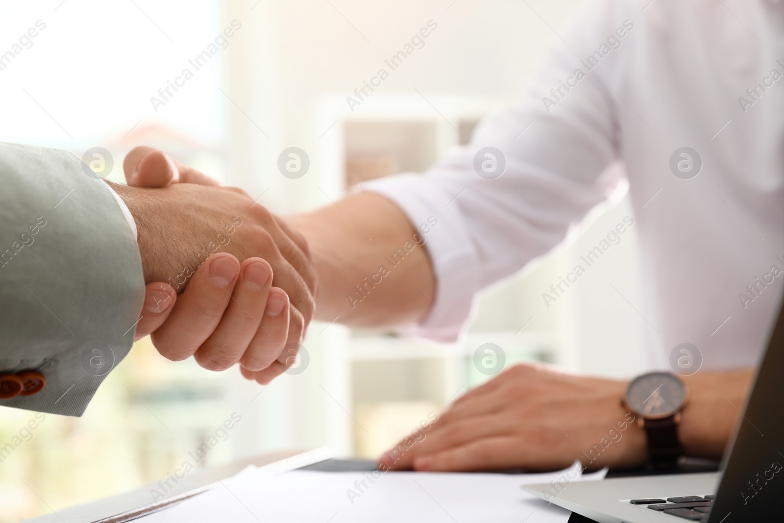 Photo of Business partners shaking hands at table after meeting in office, closeup