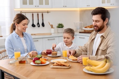 Photo of Happy family having breakfast at table in kitchen