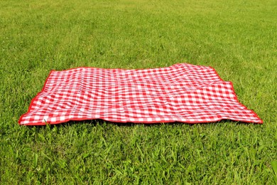 Photo of Checkered picnic tablecloth on fresh green grass outdoors