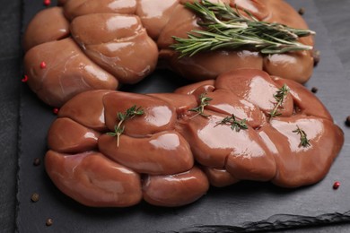 Fresh raw kidneys with rosemary and thyme on black table, closeup