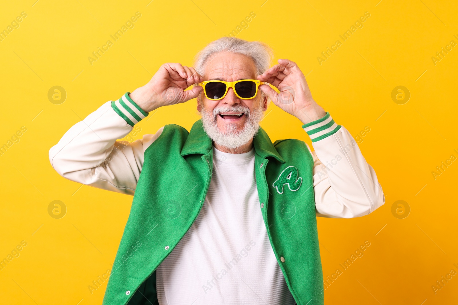 Photo of Portrait of grandpa with stylish sunglasses on yellow background