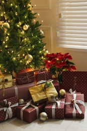 Photo of Many different gifts under Christmas tree indoors