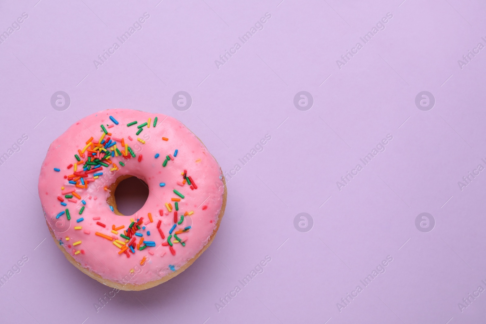 Photo of Tasty glazed donut decorated with sprinkles on purple background, top view. Space for text