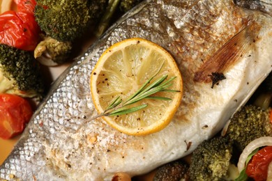 Photo of Delicious baked fish and vegetables on plate, top view