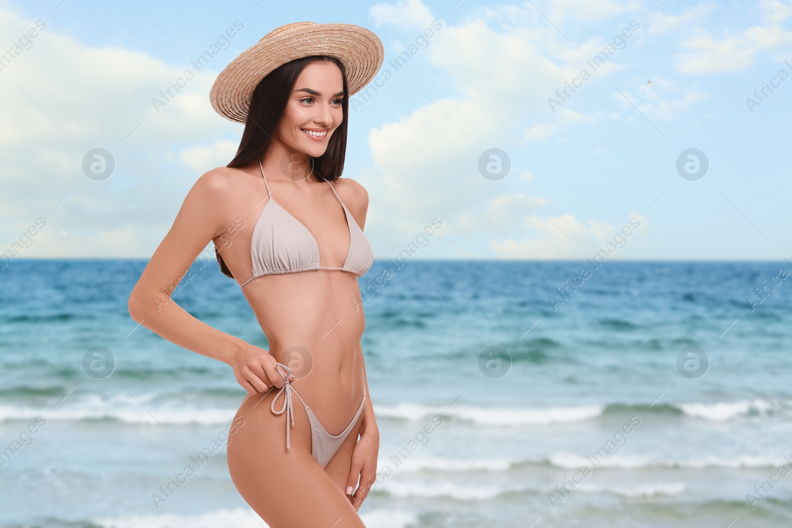 Image of Happy woman in stylish bikini and hat near sea, space for text