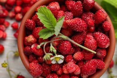 Photo of Fresh wild strawberries, flower and leaves on white table, flat lay