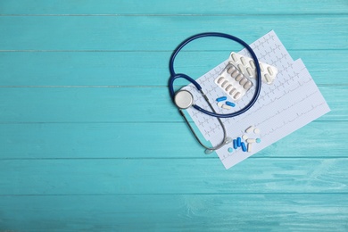 Flat lay composition with stethoscope and pills on wooden background. Cardiology service