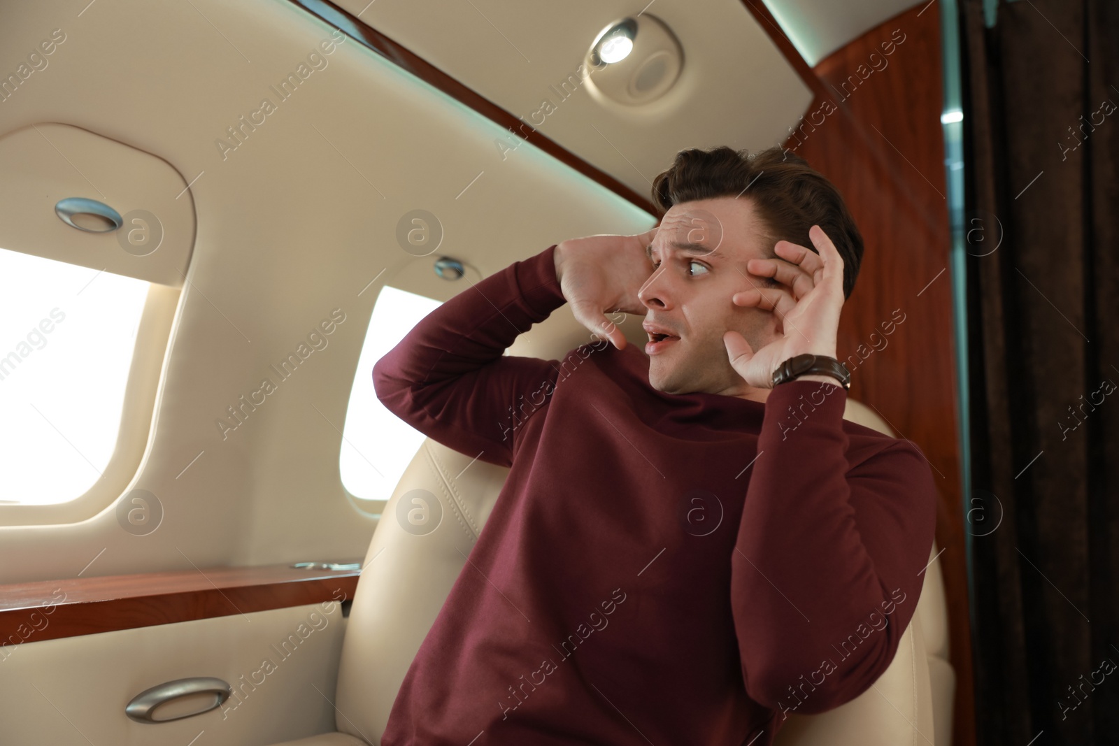 Photo of Scared young man suffering from aviophobia in airplane