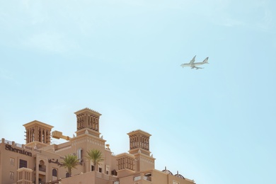 Photo of SHARJAH, UNITED ARAB EMIRATES - NOVEMBER 04, 2018: Modern airplane in sky over Sheraton resort on sunny day