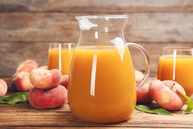 Photo of Natural peach juice and fresh fruits on wooden table