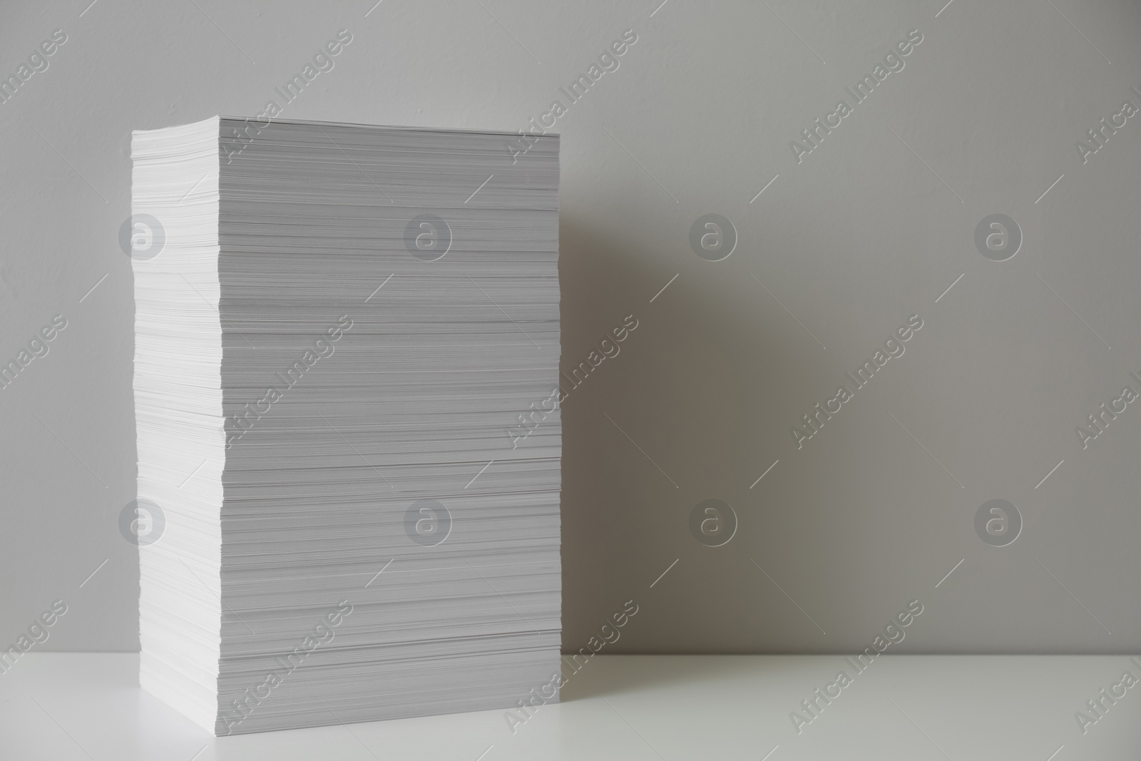 Photo of Stack of paper sheets on white table. Space for text