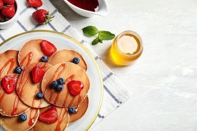 Tasty pancakes with berries served on light table, flat lay. Space for text