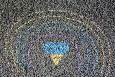 Photo of Rainbow with heart drawn by blue and yellow chalk on asphalt, top view