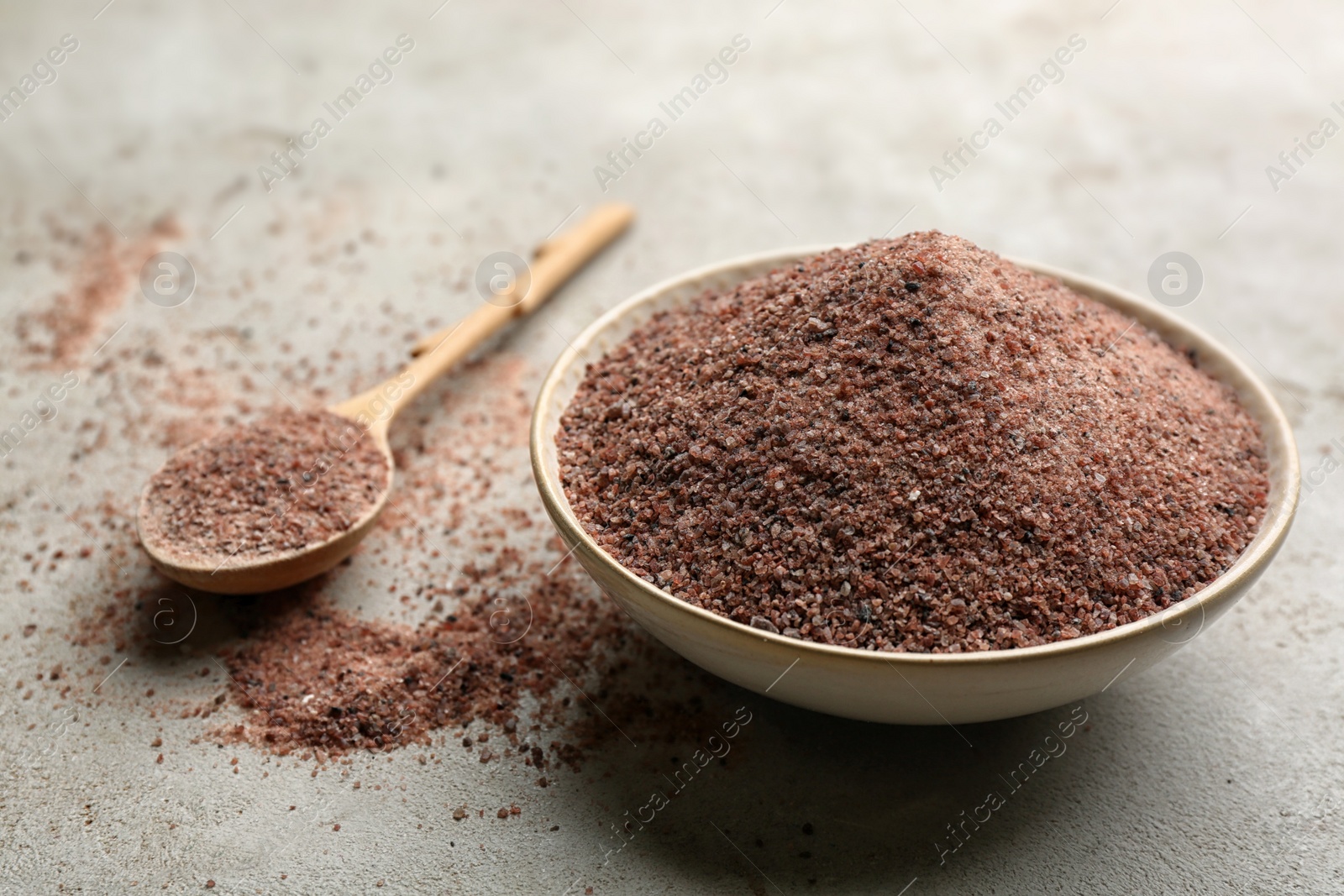 Photo of Ground black salt in bowl on grey table