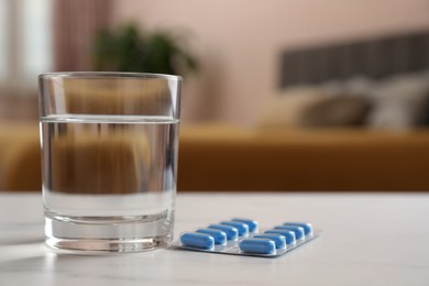 Glass of water and pills on white table indoors, space for text. Potency problem concept