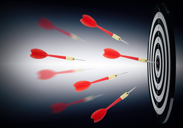 Board and red darts on dark background