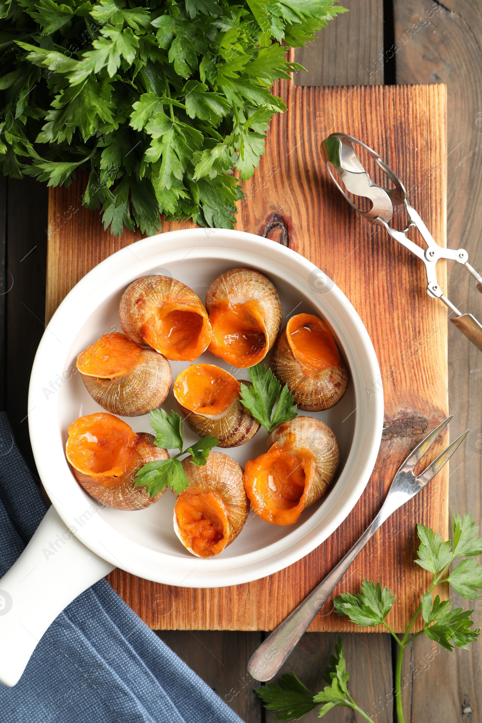 Photo of Delicious cooked snails served on wooden table, flat lay