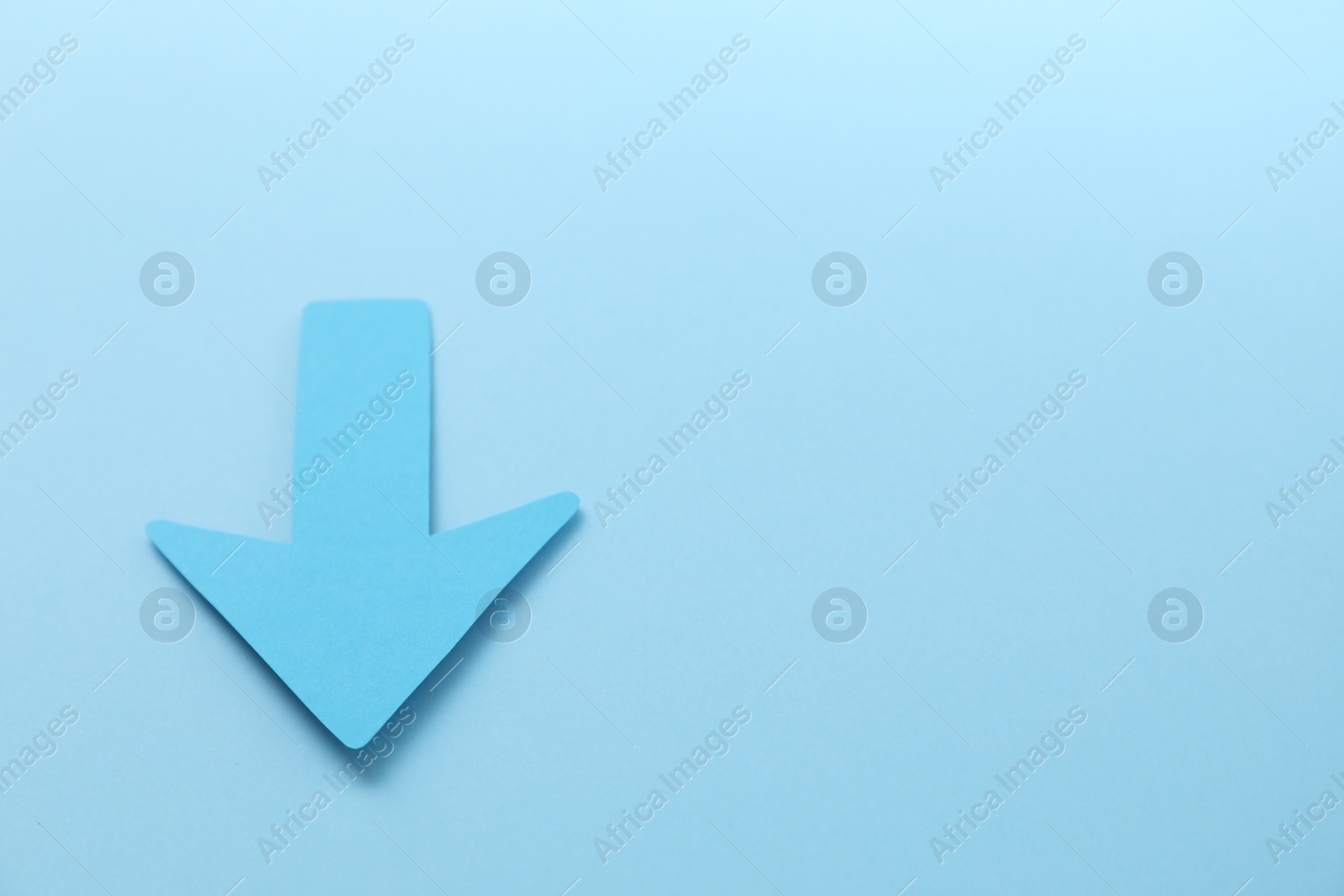 Photo of One paper arrow on light blue background, above view. Space for text