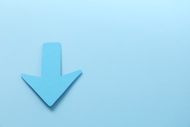 Photo of One paper arrow on light blue background, above view. Space for text