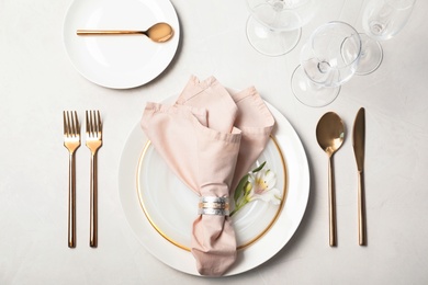 Festive table setting with plates, glasses, cutlery and napkin on light background, flat lay