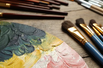 Photo of Brushes and palette on wooden table, closeup