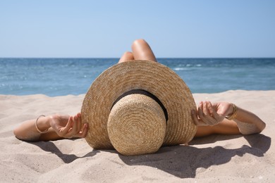 Photo of Woman with straw hat lying on sandy beach near sea 