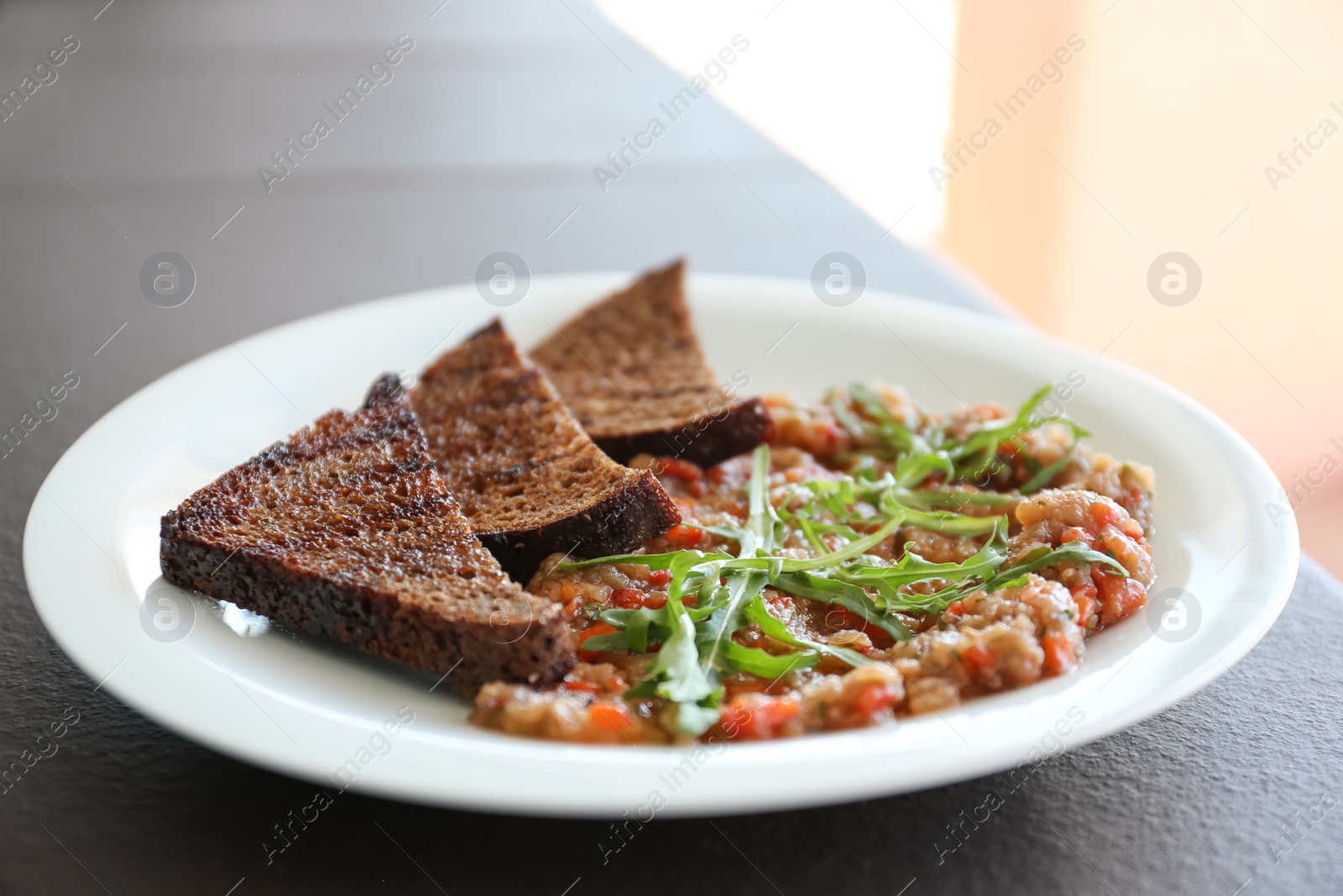 Photo of Delicious salad with roasted eggplant and bread on plate