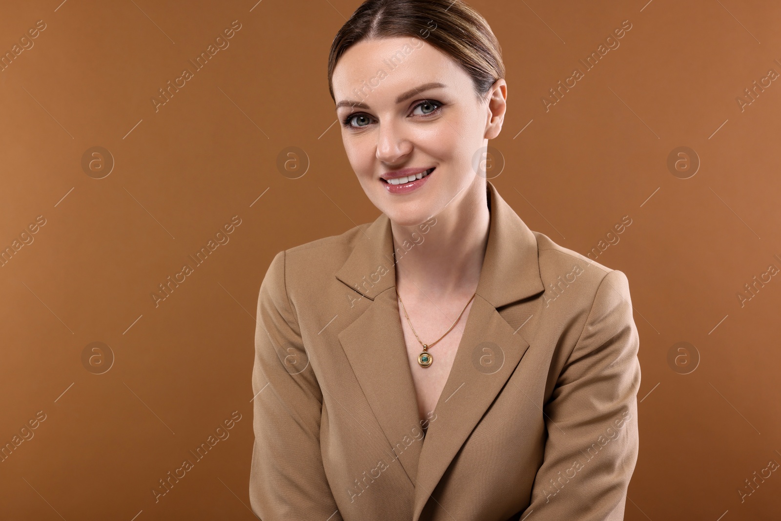 Photo of Beautiful woman with elegant necklace on brown background