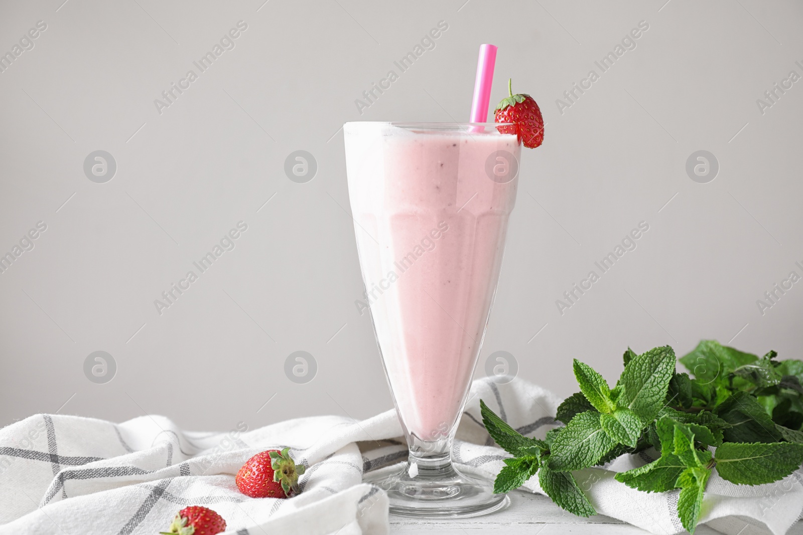 Photo of Tasty strawberry milk shake in glass on table