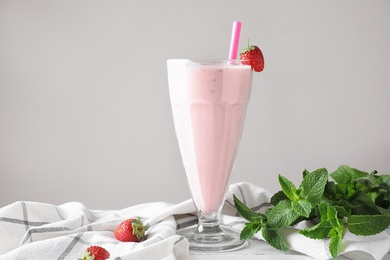 Tasty strawberry milk shake in glass on table